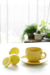 cup of tea with fresh yellow lemons on white background