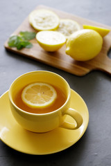 cup of tea with fresh yellow lemons on black background