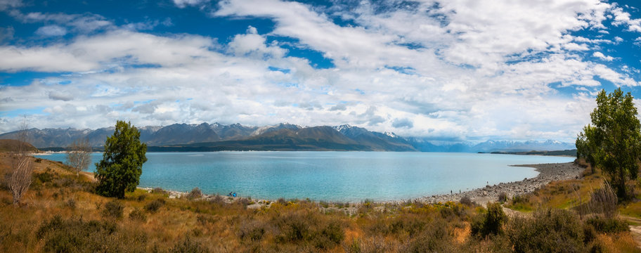 Panoramic view of Lake Pukaki, a glacial alpine lake in Mackenzie Basin, one of the iconic destinations set in a glacier-carved valley with snow-capped mountain peaks in New Zealand's South Island.