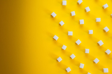 Refined sugar cubes shot on a yellow background. Background for sweets, food and drinks.