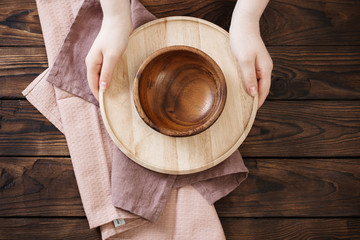 female hands and wooden dishes on old wooden table