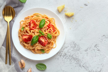Pasta with cherry tomatoes, cheese and basil on a light background