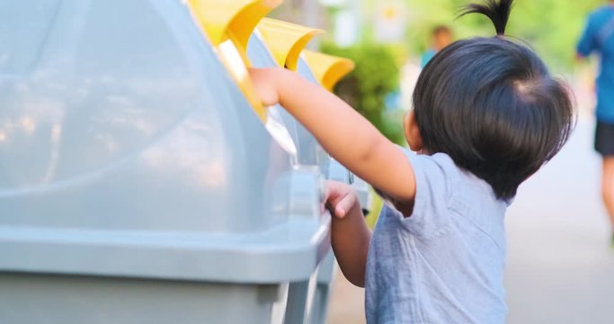 Little boy take trash to plastic bin in city park keep encironment clean concept