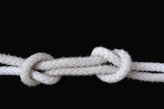A white rope tied with fisherman knot on black background.