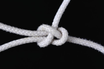 A white rope tied with sheet bend knot on black background.