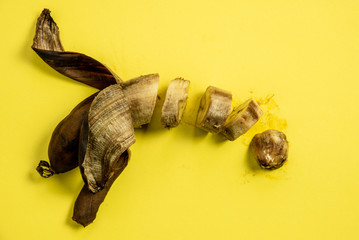 Rotten unhealthy banana on a yellow background