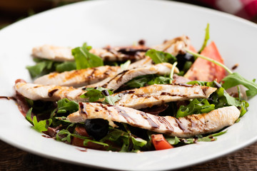 Roasted chicken with rocket salad in white bowl on wood table
