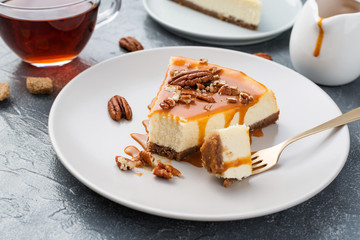 Portion of classic cheesecake with caramel sauce and pecan nuts.