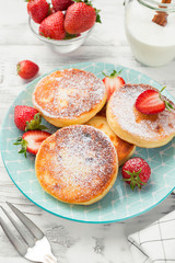 Cottage cheese pancakes with sliced strawberry on white background for breakfast.