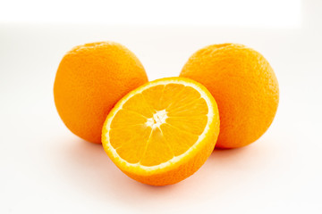 Three oranges on a white background, one cut in half
