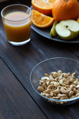 cashew nuts and juice next to other fruits on a black wooden table