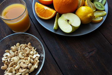 cashew nuts and juice next to other fruits on a black wooden table