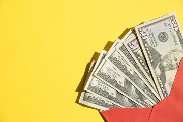 A stack of US dollar , currency bills in an open red paper envelope, isolated against yellow.Online Shopping.wealth and prosperity. Cash money in the envelope . bonus, reward, benefits concept.Copy