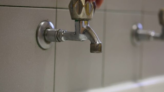 hand of the person who closes the tap so as not to waste water unnecessarily