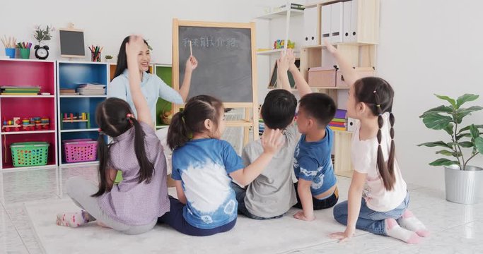 Asian female teacher teaching student to chinese language at school. Group of student listen teacher at classroom.