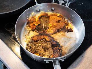 steel stewpan with crust of food burned while cooking on electric stove in home kitchen