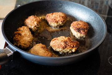 frying of russian Kotleta (minced beef steaks breaded with flour) in pan on ceramic stove at home kitchen
