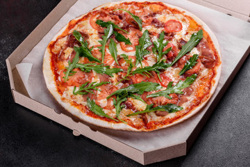 Fresh pizza baked in oven with arugula, salami, cherry tomatoes and mozzarella