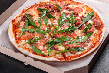 Fresh pizza baked in oven with arugula, salami, cherry tomatoes and mozzarella