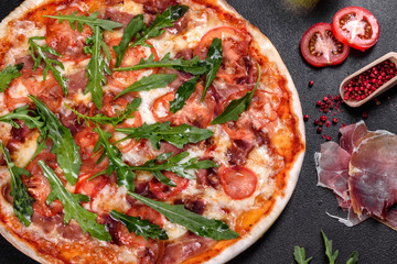 Fresh pizza baked in oven with arugula, salami, cherry tomatoes and mozzarella