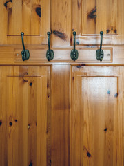 Metal hooks for clothing on a wooden door. Vertical image.