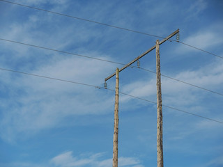 Wooden pole with wire for electricity against blue cloudy sky, copy space. Industry concept.
