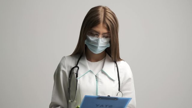 Doctor in a medical gown shows a folder with the text stay at home