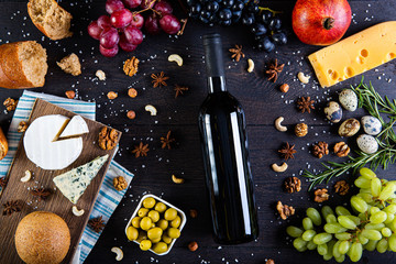 Assortment of cheeses, a bottle of wine, honey, nuts and spices, on a wooden table. Top view. Free space for text.