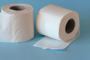 Two rolls of white clean toilet paper on a blue background