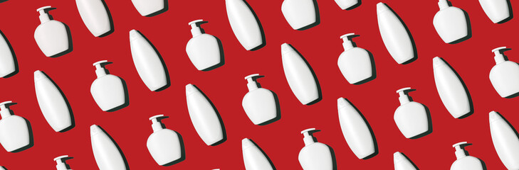 Shampoo and soap bottles pattern on red background. Top view. Flat lay. Creative design for packaging. Personal care products, spa cosmetic, beauty treatment. Hygiene plastic bottle, body care kit