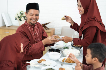 Muslim family sit to eat when breaking fast together at home