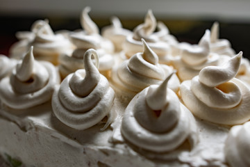 Cream dessert of airy Italian meringue. Whipped egg whites with hot sugar syrup. Light delicate cake cream in the form of a twisted peak on the top of the head in a spiral