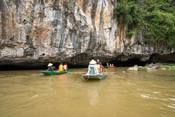 The tourist on cruise local boat, the local people rowing the boat by foots is signature of travel in "Ninh Binh" Hanoi city, Vietnam