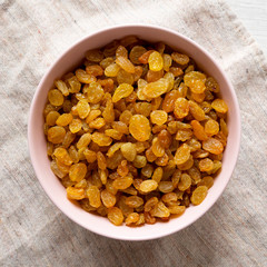 Golden Raisins in a Pink Bowl on cloth, top view. Flat lay, overhead, from above. Close-up.