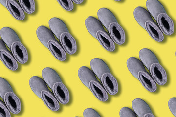 Pattern of grey ugg boots on yellow background. Creative design for packaging. Winter concept. Christmas and new year holiday.