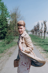 a girl with short blond hair walks around the city in a raincoat blooming in spring