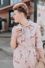 Obraz premium a girl with short blond hair walks around the city and drinks coffee in the blooming spring