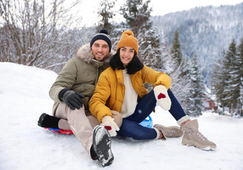 Obraz premium Happy couple sliding on snowy hill. Winter vacation