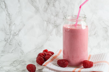 Jar with rasberry smoothie and fresh rasberry on tawel on white background.