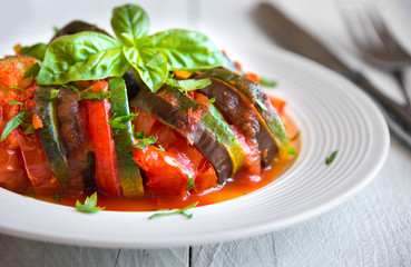 Homemade ratatouille made with sliced vegetables: zucchini, tomatoes and eggplant. Delicious vegan dish