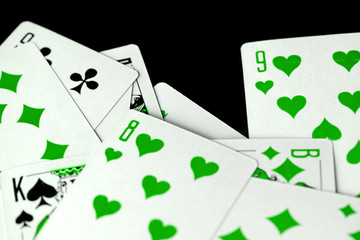 Playing cards unusual green color scattered on a black surface close-up. Gambling background