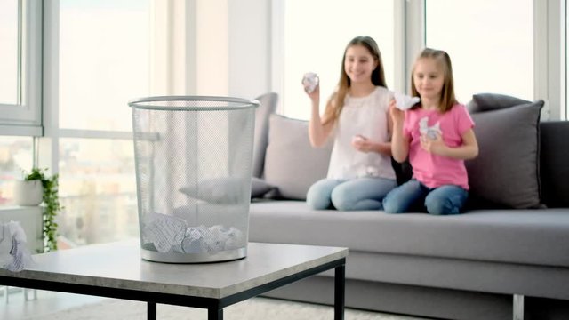 Paper basket on foreground and girls throwing balls inside