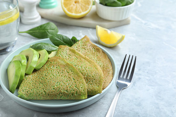 Delicious spinach crepes with avocado served on marble table