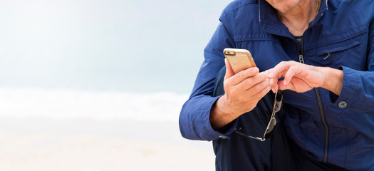 senior man using mobile phone on the beach