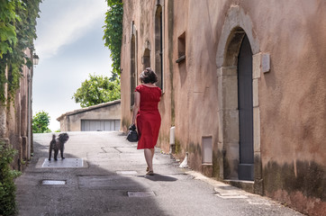Fototapeta na wymiar Junge Frau mit rotem Kleid im Dorf Joucas in der Provence