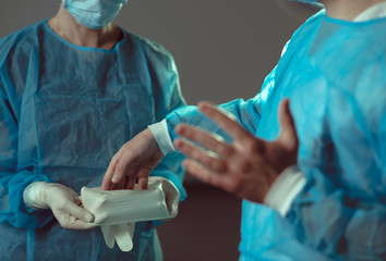 Nurse helping doctor prepare for surgical operation