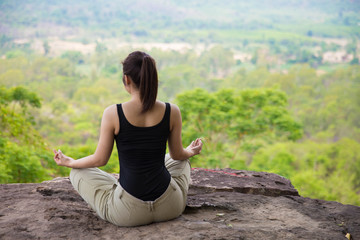 young woman doing yoga exercise on the top of the mountain 