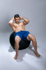 Fototapeta na wymiar Attractive young man using exercise ball. Attractive young man exercising abs .