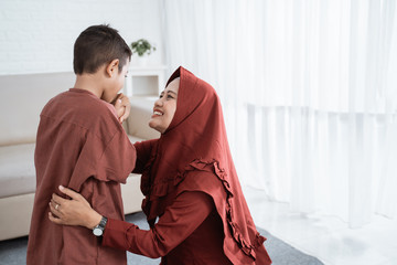 child kissing his mother's hand to apologize and say happy Eid day