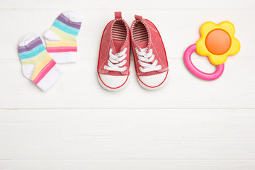 Child's booties, teether and socks on white wooden table, flat lay. Space for text